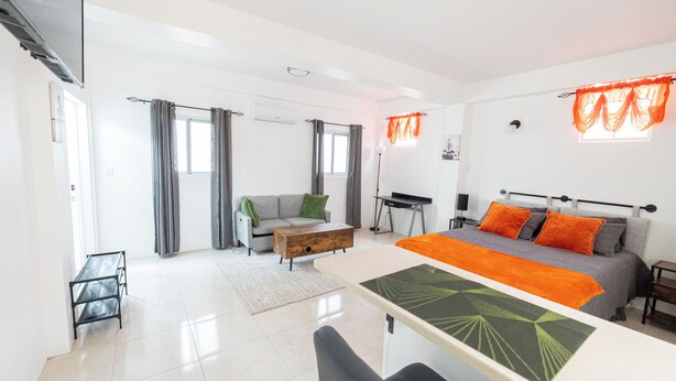 A modern bedroom with a large bed, a desk, a sofa, and a dining table. - Hilltop View: Convenient & Peaceful Studio Haven (Cedar Valley Mill Road)