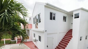A two-story building with a red staircase leading to the upper floor. - Hilltop View: Convenient & Peaceful Studio Haven (Cedar Valley Mill Road)