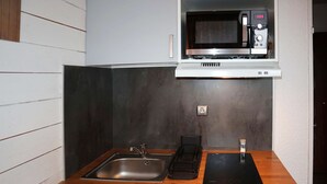 Une cuisine compacte équipée d’un four à micro-ondes encastré, d’un évier et d’un petit réfrigérateur.