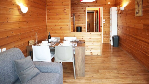 A wooden cabin interior with a dining area, a sofa, and a kitchen. - Studio for 4 people in the heart of the resort of Les Orres 1650 (LES ORRES 1650)