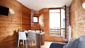 L’intérieur d’un chalet en bois comprend un coin repas, un canapé et une grande fenêtre.