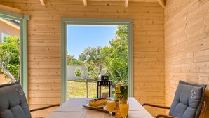 A wooden cabin with a table set for two, featuring a placemat, a plate with food, and glasses of orange juice. - Happy Home Rab by Interhome (Rab/Rab)