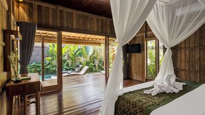 A room with a bed, a TV, and a view of a garden. - The Ulon Ubud Villa (Ubud)