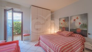 Een slaapkamer met een bed, een kledingkast, een stoel en een schilderij aan de muur.