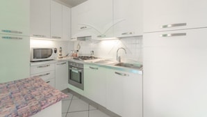 Een moderne keuken met witte kastjes, een magnetron, kookplaat en spoelbak.