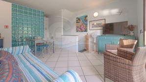 Een hotelkamer met een bed, een bureau, een stoel, een televisie en een kast.