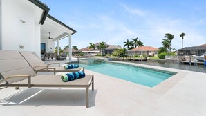 A pool area with lounge chairs and a covered seating area. - New Construction, Immaculate Canal Home; Wide Water Views, Pool, Spa, Dock & More ~Great Location! (Marco Island)