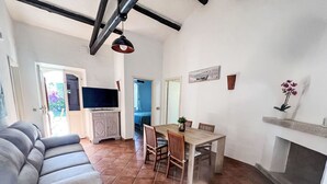 Un salon comprenant un canapé, un téléviseur, une table à manger avec des chaises et une cheminée.