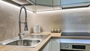 Une cuisine moderne dotée d’un évier en acier inoxydable, d’un four encastré et d’un plan de travail en bois.