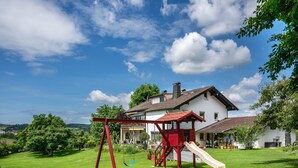 A house with a swing set and slide in the yard. - Köberich Apartment with Mountain View, Private Terrace and Large Garden (Waging am See)