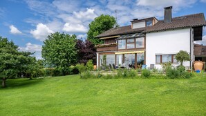A two-story house with a large lawn, a patio with outdoor furniture, and a visible chimney. - Köberich Apartment with Mountain View, Private Terrace and Large Garden (Waging am See)