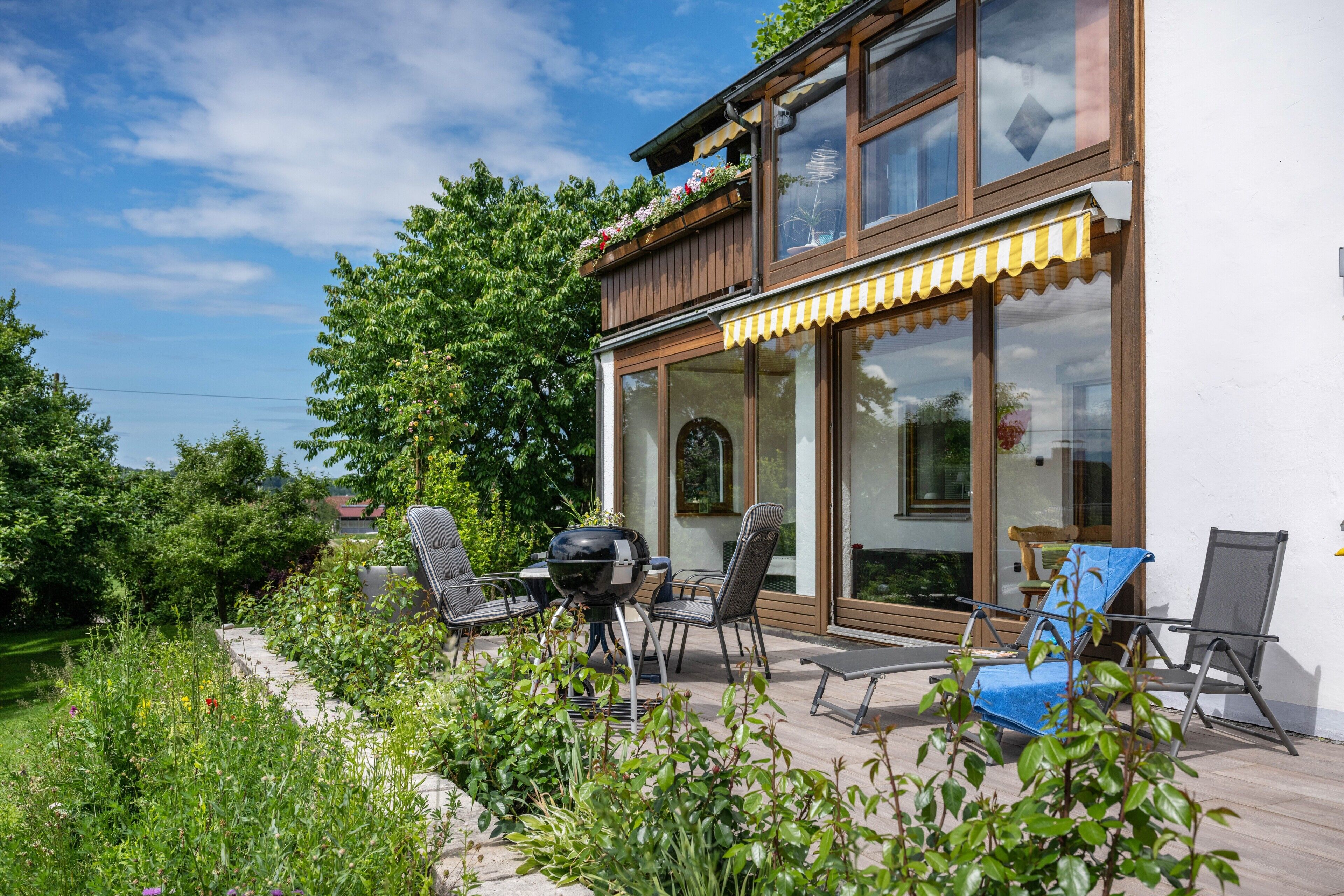 Une maison moderne dotée d’un patio, d’un espace salon extérieur et d’un barbecue.