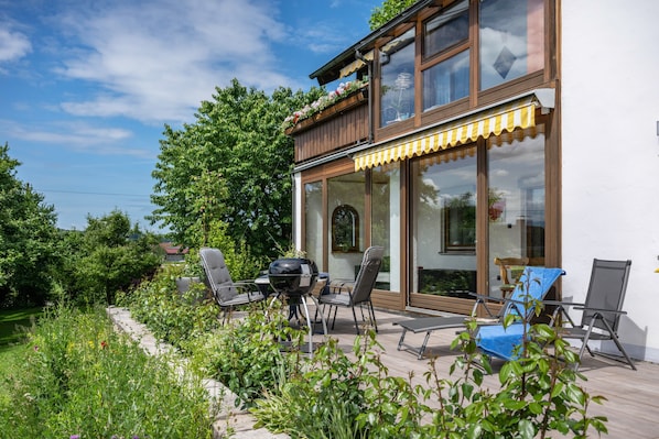 Une maison moderne dotée d’un patio, d’un espace salon extérieur et d’un barbecue.