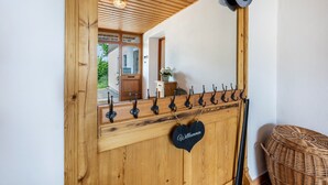 A wooden reception desk with a heart-shaped sign, a hat rack, and a wicker bench. - Köberich Apartment with Mountain View, Private Terrace and Large Garden (Waging am See)