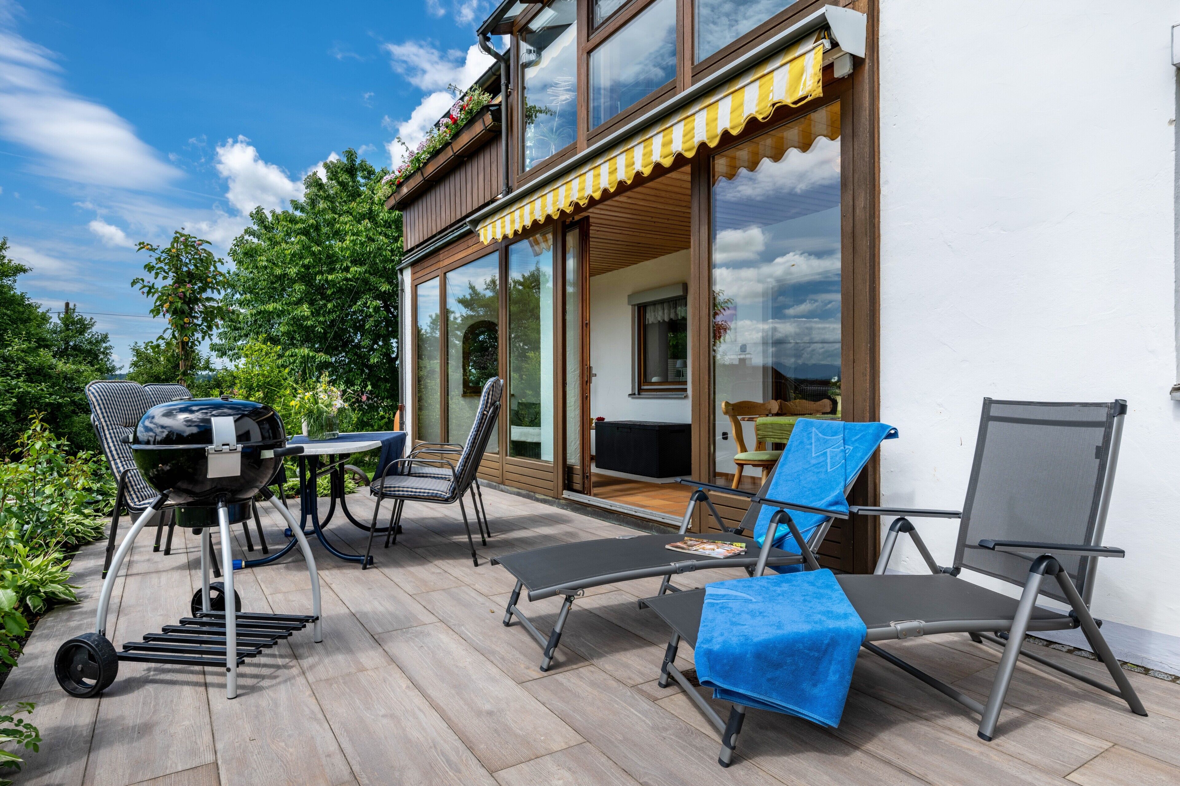 Une terrasse extérieure équipée d’un barbecue, de chaises longues et d’une table.