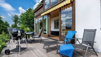 Une terrasse extérieure équipée d’un barbecue, de chaises longues et d’une table.