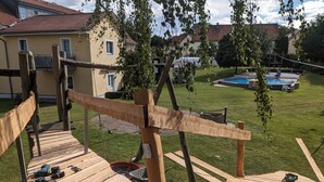 Una terraza de madera con herramientas, una piscina y una casa al fondo.