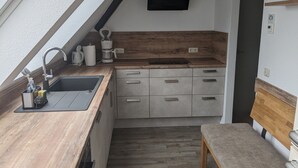 Una cocina compacta con lavamanos, cafetera y encimera de madera.