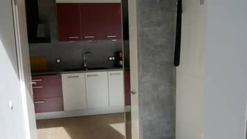 Une cuisine moderne dotée d’une cuisinière intégrée, de meubles blancs et rouges, et d’un plan de travail gris.