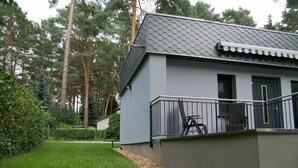 A modern house with a grey exterior, a balcony with a metal railing, and a well-maintained lawn. - Holiday Home 'Am Kiefernweg 17' with Private Terrace (Schwielochsee)