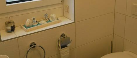 A bathroom with a toilet, a sink with a mirror above it, a towel rack, and a window with frosted glass.