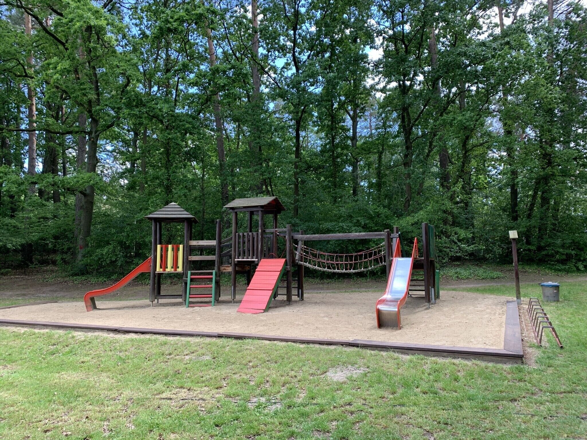 Ein Spielplatz mit Rutsche, Klettergerüsten und einer Hängebrücke.