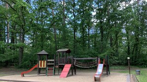 Un parque infantil con tobogán, estructuras para escalar y un puente colgante.
