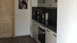 Una cocina con armarios blancos, una puerta de madera y una encimera negra.