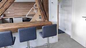 Een moderne keuken met een houten kookeiland, drie barkrukken en een witte deur.
