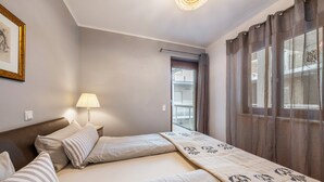Ein Hotelzimmer mit Bett, Nachttisch, Lampe und Blick ins Freie.