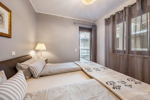 Hotellihuone, jossa on sänky, yöpöytä, lamppu ja näkymä ulos.