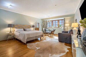 A bedroom with a bed, bedside tables, a desk, a chair, a cowhide rug, and a window with curtains.