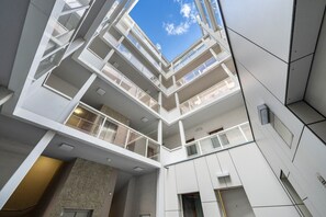 Un atrium à plusieurs niveaux, doté de rampes en verre et offrant une vue dégagée sur le ciel.