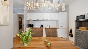 Una cocina moderna con armarios blancos, una mesa de comedor de madera y una lámpara colgante.