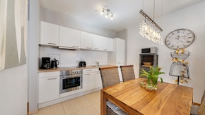 Una cocina moderna con armarios blancos, una mesa de comedor de madera y un reloj de pared.