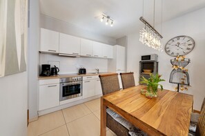 Une cuisine moderne avec des meubles blancs, une table à manger en bois et une horloge murale.