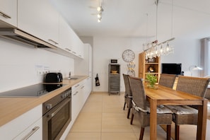Une cuisine moderne avec un coin repas, des appareils en acier inoxydable et une table en bois.