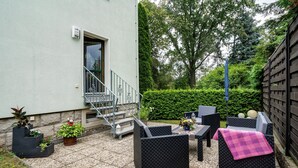 A patio with outdoor furniture, a staircase, and potted plants.