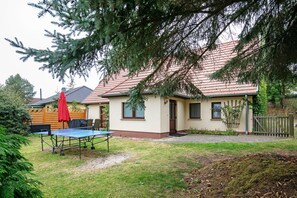 A house with a red roof, a small front yard, and a table with a red umbrella.