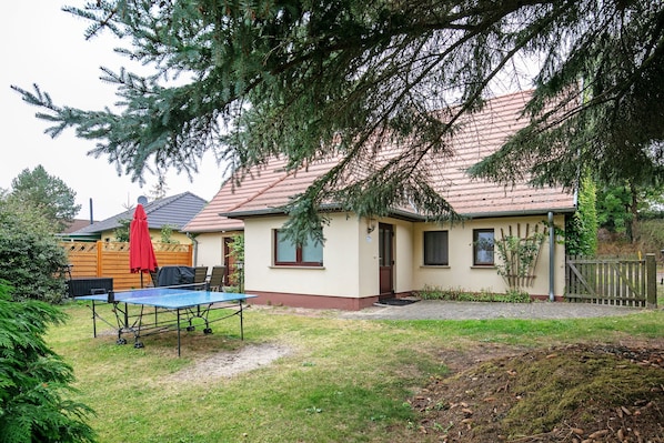 A house with a red roof, a small front yard, and a table with a red umbrella. - Holiday Home 'Ferienhaus Sonnenhof' with Private Terrace, Private Garden and Wi-Fi (Oberuckersee)