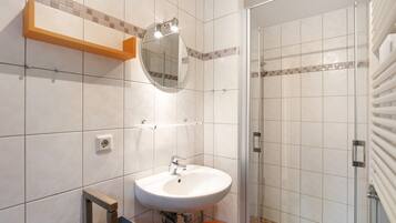 Une salle de bain avec un lavabo, un miroir et une douche.