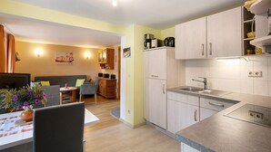 A modern kitchen with light wood cabinets, a built-in oven, and a sink. - Holiday Home 'Ferienhaus Sonnenhof' with Private Terrace, Private Garden and Wi-Fi (Oberuckersee)