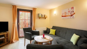 A living room with a grey sofa, a wooden coffee table, a flat-screen TV, and a radiator. - Holiday Home 'Ferienhaus Sonnenhof' with Private Terrace, Private Garden and Wi-Fi (Oberuckersee)