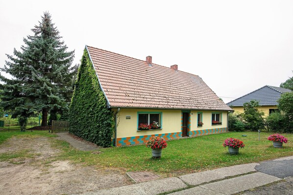 A single-story house with a sloped roof, a small front porch, and a paved driveway.