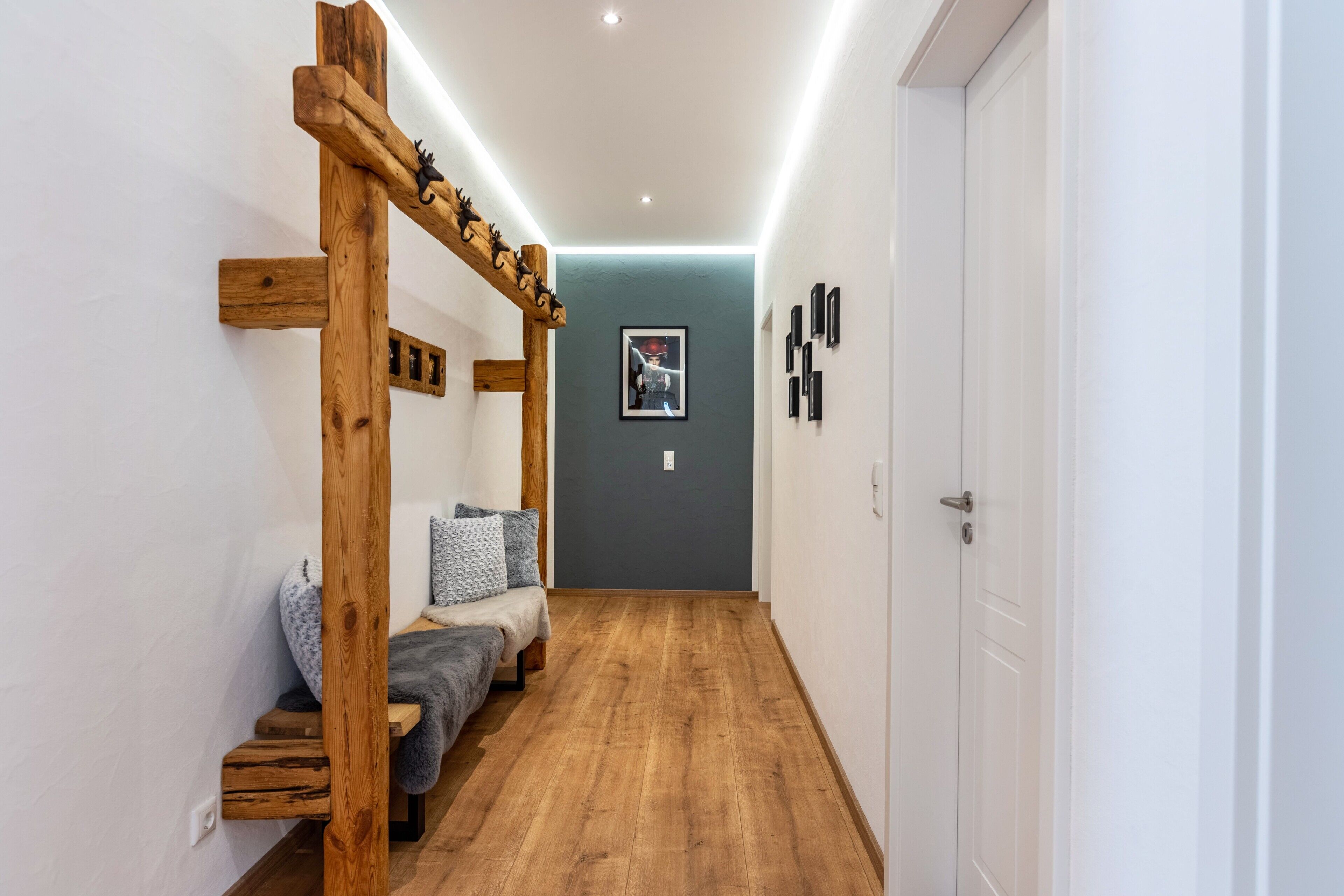 A hallway with a wooden bench, a door, and a framed picture on the wall.