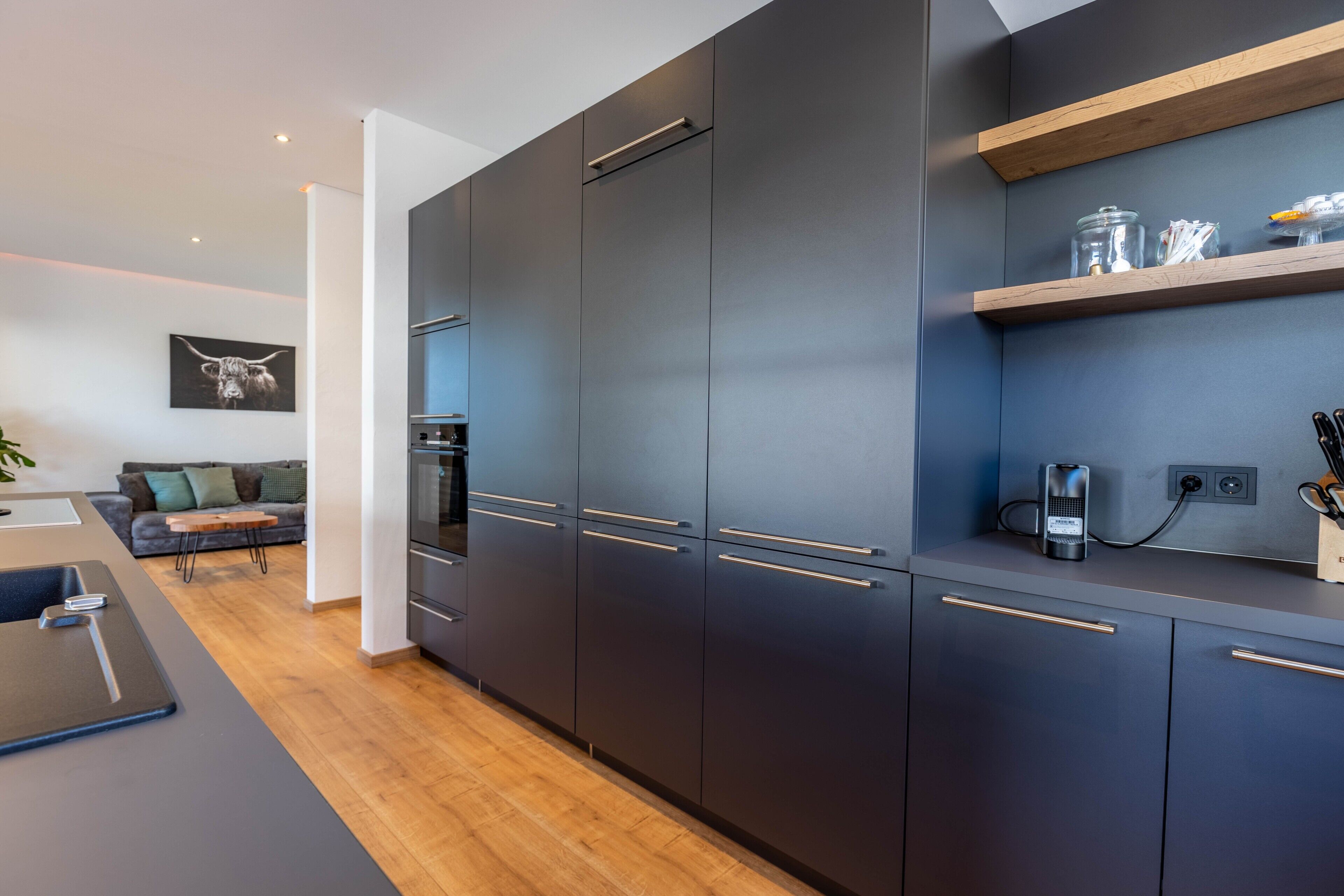 Una cucina moderna con mobili scuri, un piano di lavoro in legno e un forno integrato.