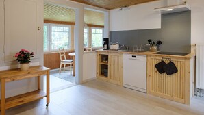 A modern kitchen with wooden cabinets, a built-in oven, and a window overlooking a garden. - Apartment 'Loschwitz' with Wi-Fi (Dresden)