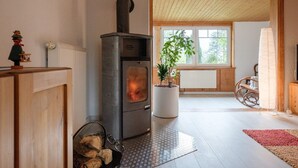 A cozy room with a wood-burning stove, a potted plant, a rocking chair, and a view through a window. - Apartment 'Loschwitz' with Wi-Fi (Dresden)