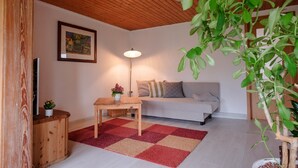 A cozy living room with a wooden ceiling, a sofa, a table with a lamp, and a plant. - Apartment 'Loschwitz' with Wi-Fi (Dresden)