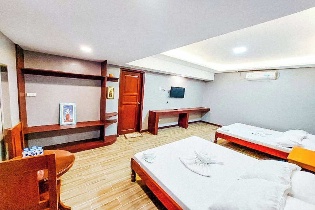 Ein Hotelzimmer mit zwei Betten, einem Schreibtisch, einem Kleiderschrank und einem Fernseher.